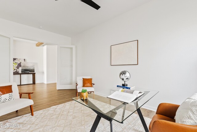 living room featuring baseboards, ceiling fan, and light wood-type flooring