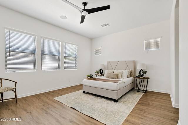 bedroom with baseboards, a ceiling fan, wood finished floors, and visible vents