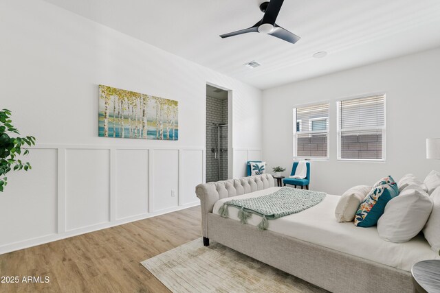 bedroom with a decorative wall, a wainscoted wall, a ceiling fan, wood finished floors, and visible vents
