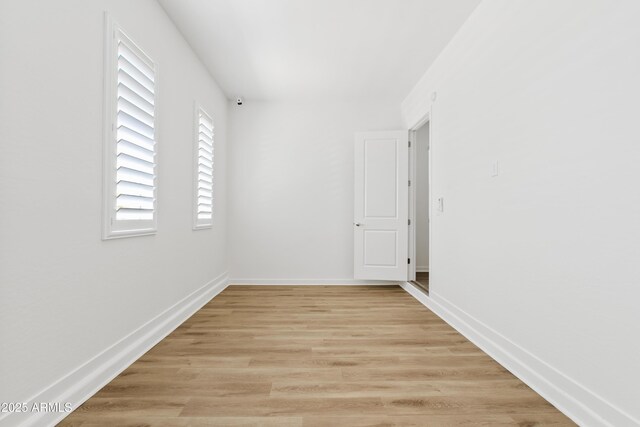 empty room featuring baseboards and light wood-type flooring