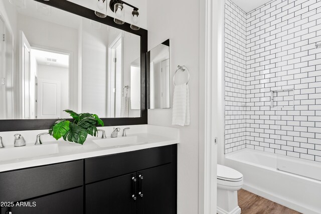 full bath featuring double vanity, toilet, a sink, and wood finished floors