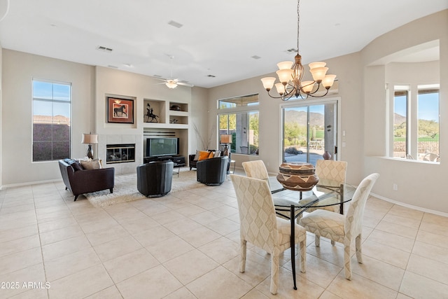 dining room with built in shelves, a wealth of natural light, a fireplace, and light tile patterned floors