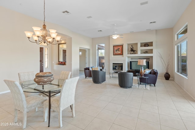 tiled dining space with built in shelves and ceiling fan with notable chandelier