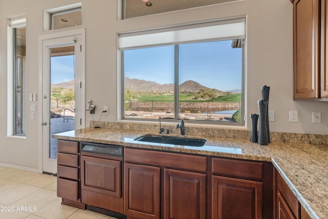 kitchen with sink, light stone counters, a mountain view, dishwashing machine, and light tile patterned floors