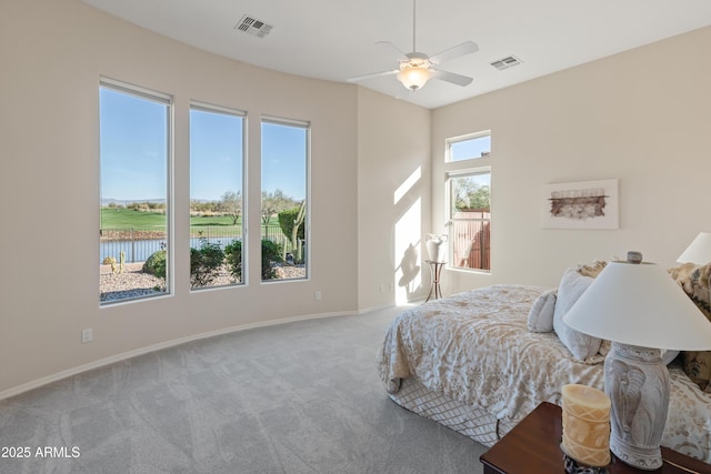 bedroom with multiple windows, carpet floors, a water view, and ceiling fan