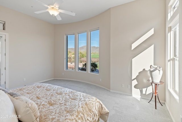 carpeted bedroom with ceiling fan, a mountain view, and multiple windows