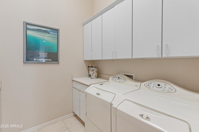 clothes washing area featuring washing machine and dryer, light tile patterned flooring, and cabinets