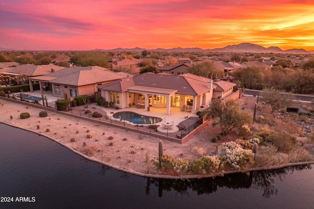 aerial view at dusk featuring a water and mountain view