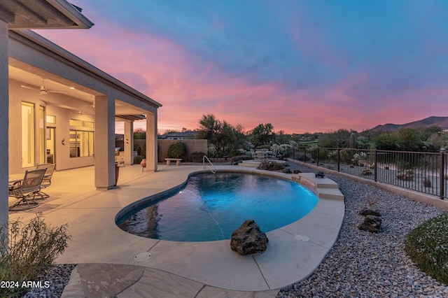 pool at dusk with a patio area and a mountain view