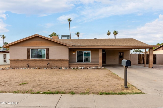 single story home with an attached carport, brick siding, driveway, and fence