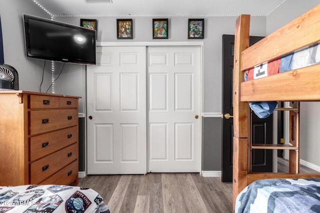 bedroom featuring a closet, visible vents, baseboards, and wood finished floors