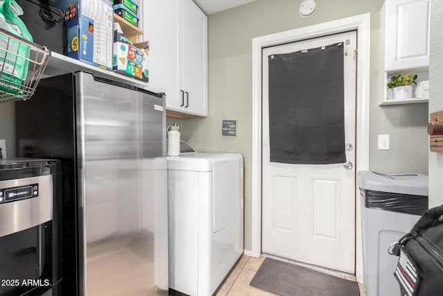 laundry room featuring cabinet space, light tile patterned floors, and washer / clothes dryer