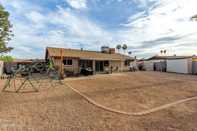 rear view of property featuring a patio, a fenced backyard, a storage unit, an outdoor structure, and central air condition unit