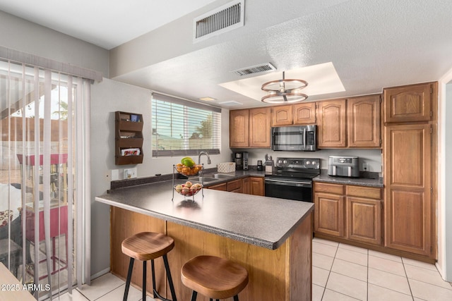 kitchen featuring visible vents, stainless steel microwave, a sink, and electric range