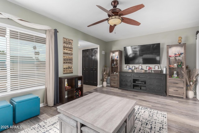 living area with ceiling fan, baseboards, and wood finished floors