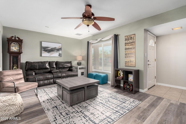 living area with light wood-type flooring, visible vents, baseboards, and a ceiling fan