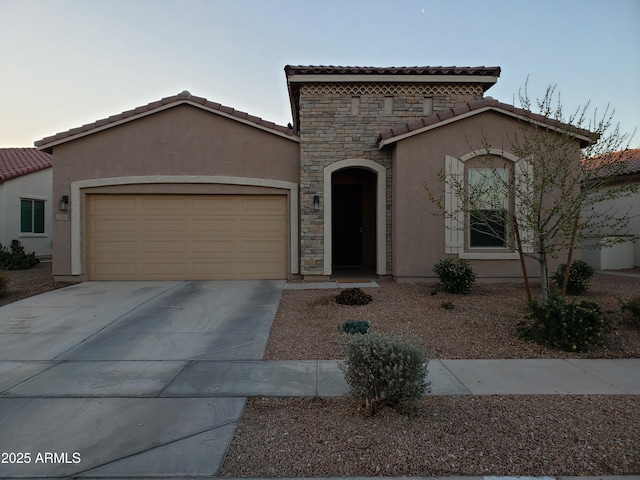 mediterranean / spanish house with an attached garage, a tile roof, concrete driveway, and stucco siding