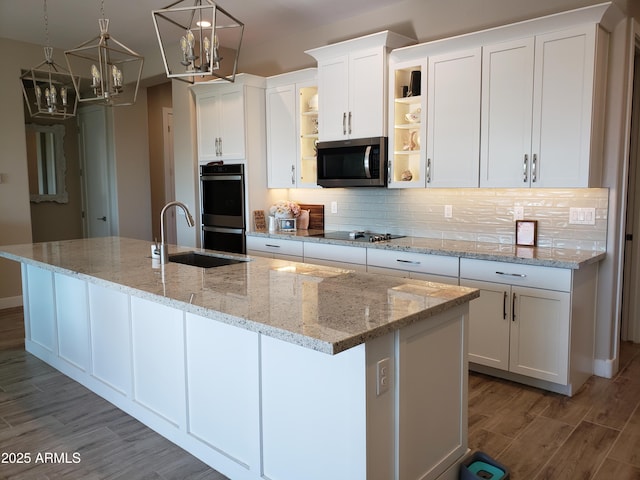 kitchen with stainless steel appliances, a sink, a kitchen island with sink, and white cabinets