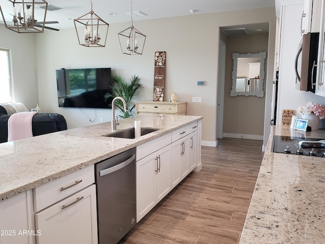 kitchen with light stone counters, pendant lighting, stainless steel appliances, white cabinetry, and a sink