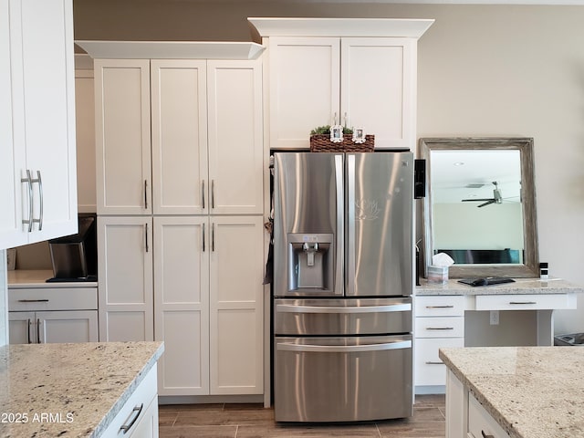 kitchen with wood finish floors, white cabinets, stainless steel refrigerator with ice dispenser, and light stone countertops