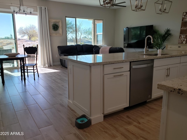 kitchen featuring a sink, white cabinets, open floor plan, dishwasher, and decorative light fixtures