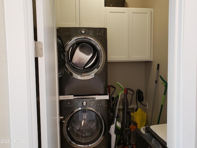 washroom with cabinet space and stacked washer and clothes dryer