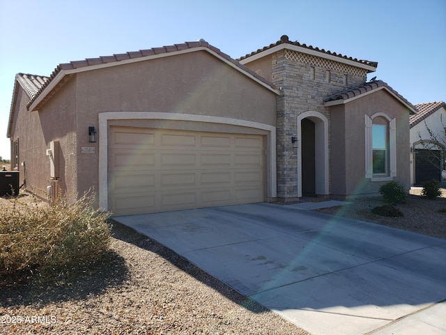 mediterranean / spanish home with a garage, central AC unit, concrete driveway, stone siding, and stucco siding