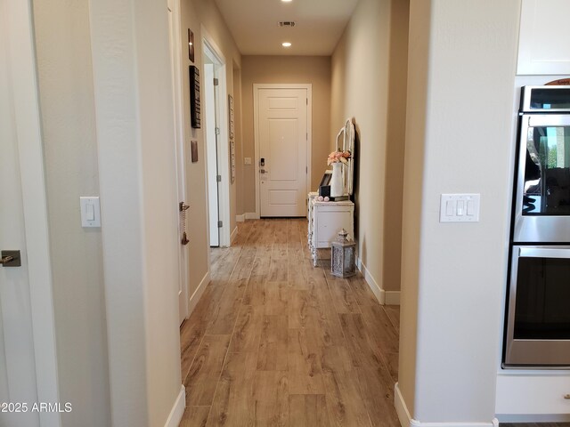 hall with light wood-style floors, recessed lighting, visible vents, and baseboards