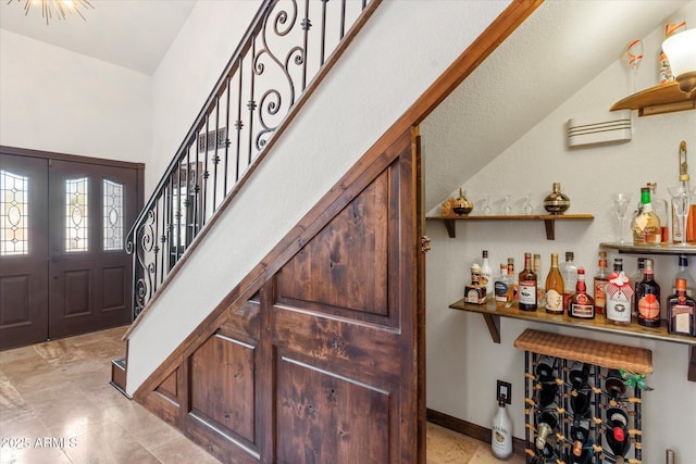 foyer entrance featuring indoor bar and lofted ceiling