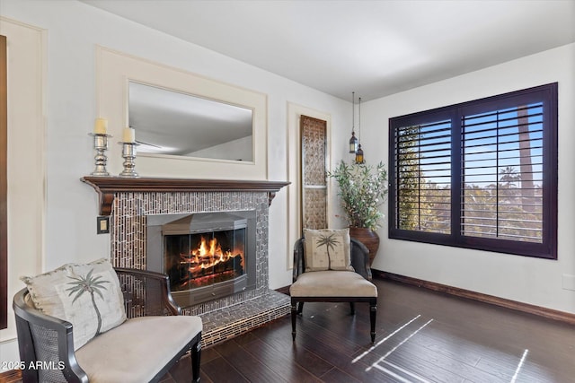 living area with dark hardwood / wood-style flooring and a tiled fireplace