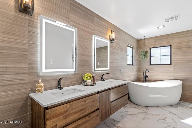 bathroom featuring a washtub, vanity, and tile walls