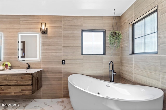 bathroom with a bathing tub, a wealth of natural light, tile walls, and vanity