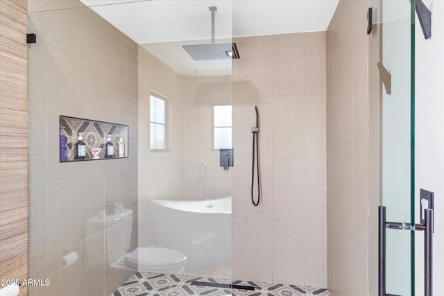 bathroom featuring toilet, plus walk in shower, and tile walls