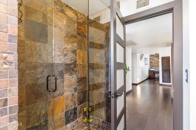 bathroom with hardwood / wood-style flooring and a shower with shower door