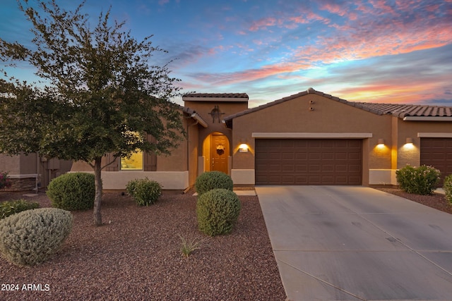 mediterranean / spanish-style home with concrete driveway, a tiled roof, stucco siding, and a garage