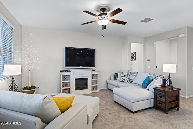 living room with ceiling fan, visible vents, baseboards, a glass covered fireplace, and light tile patterned flooring