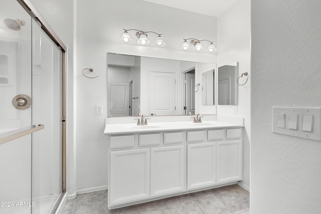 full bath with baseboards, a sink, a stall shower, and double vanity