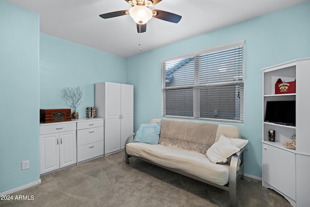 sitting room with baseboards, ceiling fan, and light carpet