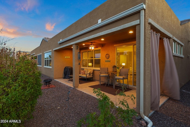 back of house with a patio, an outdoor living space with a fire pit, and stucco siding