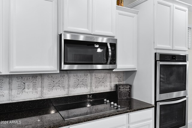 kitchen featuring dark stone countertops, stainless steel appliances, and white cabinets