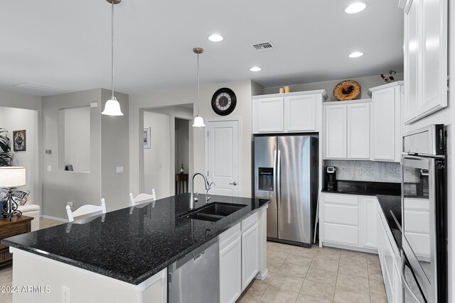 kitchen featuring hanging light fixtures, a sink, white cabinets, stainless steel appliances, and an island with sink
