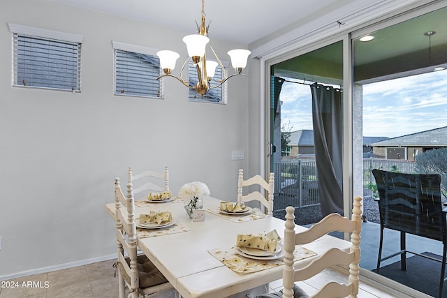 tiled dining room with an inviting chandelier and baseboards