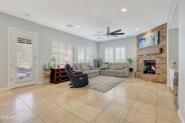 tiled living room featuring a fireplace and ceiling fan