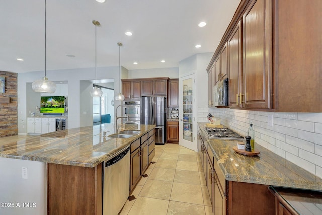 kitchen featuring sink, stainless steel appliances, hanging light fixtures, and light stone counters