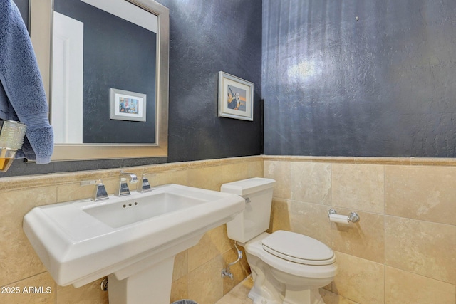 bathroom featuring sink, toilet, and tile walls