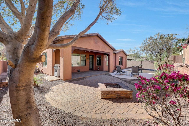 rear view of property with an outdoor fire pit and a patio