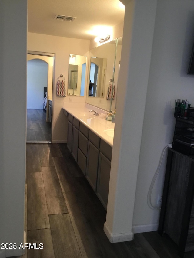 10489 S 182nd Dr, Goodyear, AZ 85338 - bathroom with baseboards, double vanity, visible vents, a sink, and wood finished floors