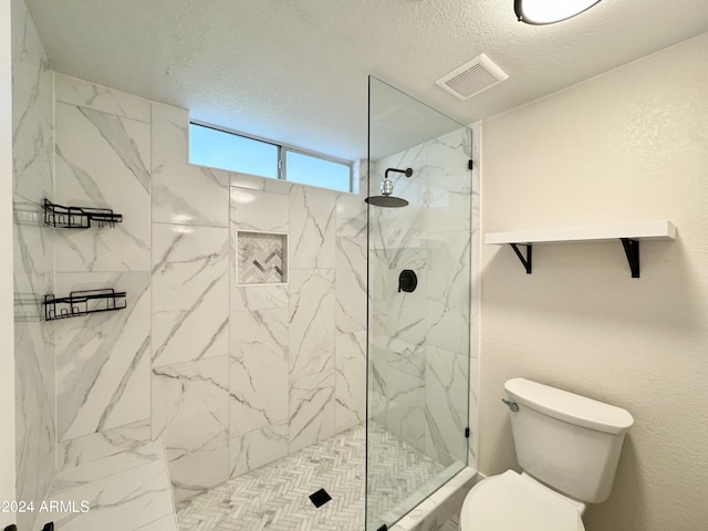 bathroom with tiled shower, a textured ceiling, and toilet