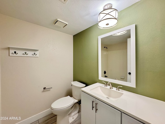 bathroom with vanity, a textured ceiling, and toilet