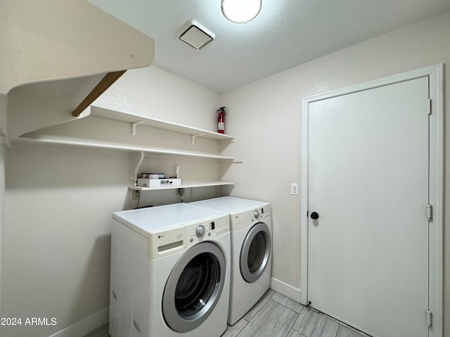 washroom with independent washer and dryer, light tile patterned floors, and a textured ceiling